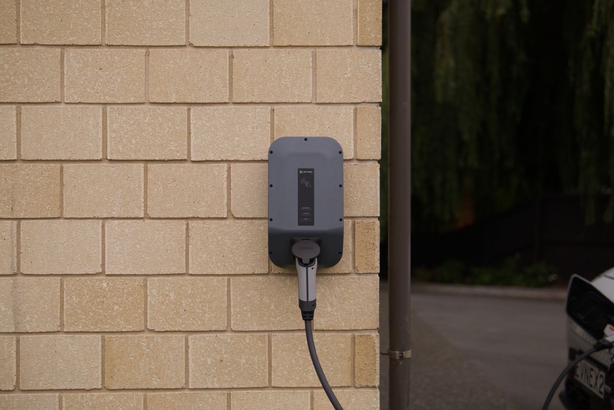 Wall-mounted EV charger installed on the brick wall of a house